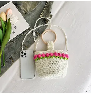 Detalle de bolso tipo cubo de ganchillo con tulipanes rosas y correa de perlas