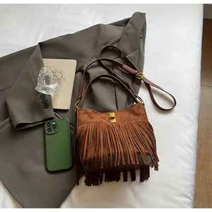 Detailed view of vintage brown suede shoulder bag with retro fringe and golden buckle