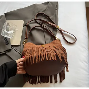 Detailed view of brown suede tassels and magnetic buckle on the vintage shoulder bag