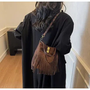 Detail of vintage brown suede bag with long tassels and gold turn-lock closure