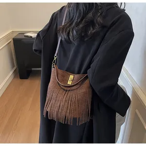 Detail shot of brown frosted bucket bag with long fringe tassels and gold twist lock