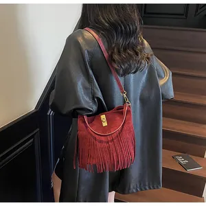 Detail of dark red matte leather bag featuring long tassels and gold metal twist lock