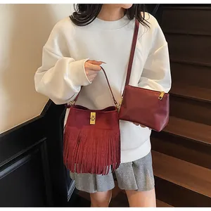 Close-up of wine red fringed bucket bag with gold clasp and matching inner pouch