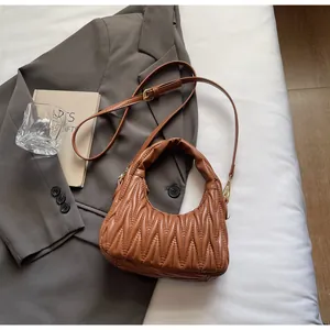 Detalle de la textura acolchada y plisada marrón de un bolso de mano moderno