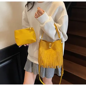 Close-up of yellow fringed bucket bag set with matching inner pouch and metal turn-lock
