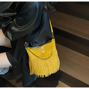Detail of yellow matte leather crossbody bag with long tassels and gold metal lock