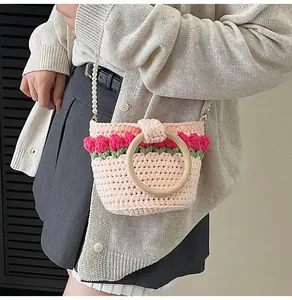 Detalle del bolso tipo cubo de punto rosa con tulipanes 3D y correa de perlas