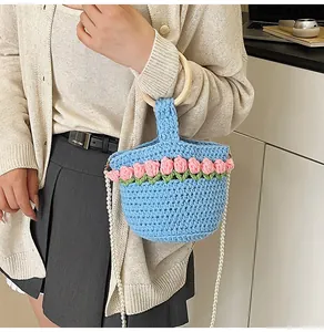 Detalle del bolso tipo saco de ganchillo azul con tulipanes rosas y correa de perlas