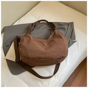 Vista detallada de bolso tote a cuadros marrones con tejido texturizado y correa ancha