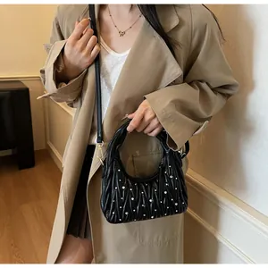 Detalle de bolso en cuero negro acolchado con pedrería y herrajes dorados sobre una modelo