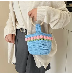 Detalle del bolso tipo cubo de punto con tulipanes rosas y correa de perlas blancas