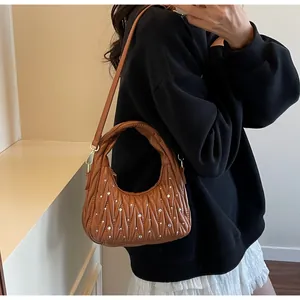 Detalle del bolso hobo acolchado marrón oscuro con adornos de pedrería y cremallera dorada