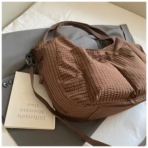 Detalle del bolso tote de cuadros marrones con bolsillos frontales y textura de tela
