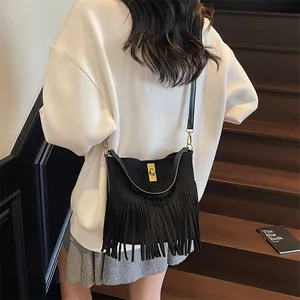 Retro black crossbody bag with fringe tassels and gold lock shown in a casual street style