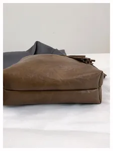Primer plano de la base ancha y las costuras del bolso tipo cubo marrón con textura