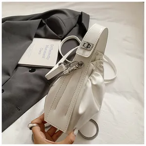 Primer plano del bolso fruncido blanco con cadena metálica plateada y cierre de giro