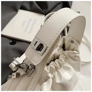 Detalle de un bolso nube plisado blanco crema con textura de cuero y cierre plateado
