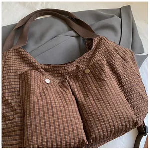 Primer plano del bolso tote de cuadros marrones con bolsillos y botones de metal plata