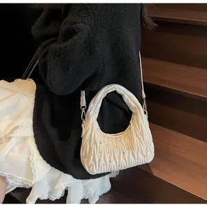 Detalle del bolso bandolera plisado con pedrería brillante y asa superior fina