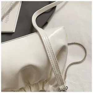 Primer plano del bolso blanco brillante con detalles plisados y correa de cadena fina