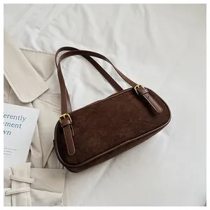 Detalle de bolso de hombro en ante marrón oscuro con hebillas metálicas doradas finas