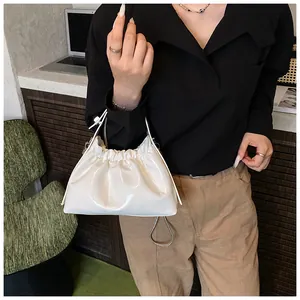 Detalle de bolso nube en charol blanco con pliegues de cordón y correa de cadena fina