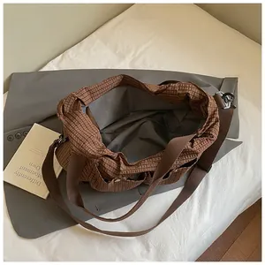 Vista detallada del bolso tote de lona a cuadros marrones con amplio espacio y bolsillos