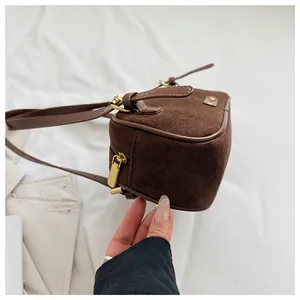 Detalle del bolso de hombro en gamuza marrón mate con herrajes de metal dorado