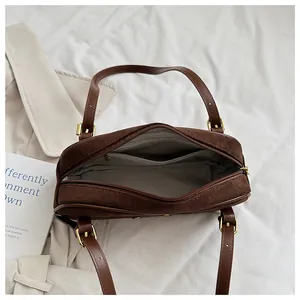 Detalle de bolso de hombro en ante marrón oscuro con forro interior y bolsillo con cremallera