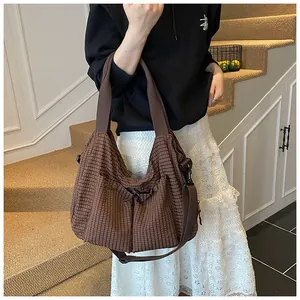 Detalle del bolso tote de cuadros marrones con correas anchas y hebilla de estilo retro