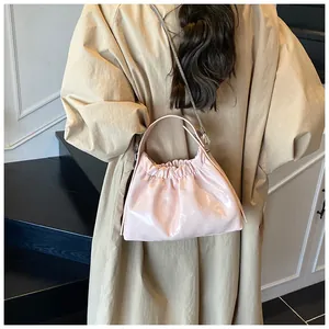 Bolso plisado rosa pálido brillante con cadena de metal sobre gabardina beige moderna