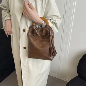 Bolso tipo cubo marrón vintage con asas de madera y borlas de cuero de estilo retro