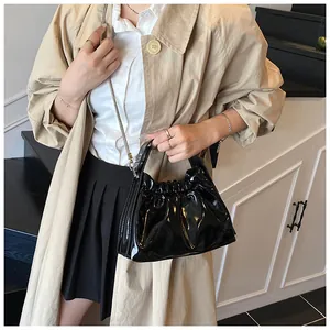 Detalle de un bolso plisado negro brillante con cadena llevado por una modelo hoy