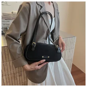 Detalle de bolso negro mate para el hombro con hebilla de metal y textura de correa