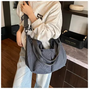 Detalle de bolso tote de cuadros azul grisáceo con bolsillos cargo llevado por la modelo