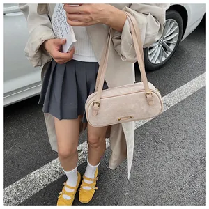 Detalle de bolso baguette beige de ante sintético con correas dobles y hebilla oro