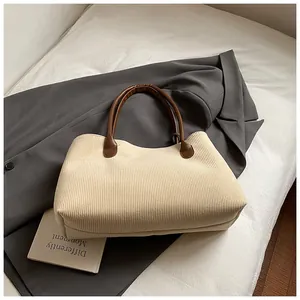Detalle de textura de pana y asa de cuero marrón en bolso tote color beige