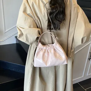 Bolso plisado de cuero rosa con cadena plateada mostrado sobre el hombro de la modelo
