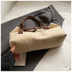 Detalle del bolso tote de pana crema con correas de cuero marrón y hebilla metálica