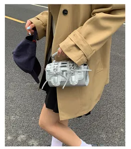 Bolso de mano plateado metalizado con encaje y lazos en un entorno urbano de moda