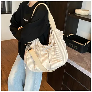 Detalle del bolso hobo de lona beige con rayas y correa ancha para el hombro