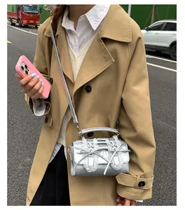 Foto estilo urbano de bolso bandolera plateado metalizado con encaje y lazo decorativo