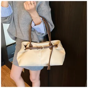 Detalle del bolso tote de pana beige con correas de cuero marrón y hebilla dorada