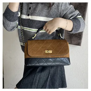 Close-up of quilted contrast panels and gold-tone twist lock on the crossbody bag