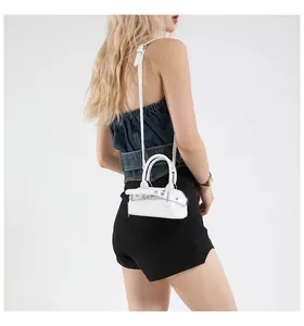 Gros plan du mini sac à main blanc brillant avec boucle décorative porté par un mannequin