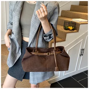 Detalle de bolso tote de pana marrón oscuro con correas de cuero y hebillas laterales