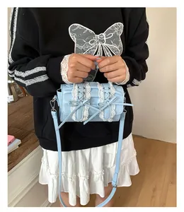 Detalle del bolso bandolera azul claro con encaje blanco y lazos usado por una modelo