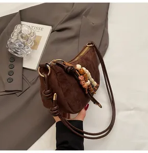 Details der Wildleder-Schultertasche mit bunten Holzperlen-Quasten und Gold-Hardware