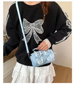 Detalle de bolso bandolera azul claro con encaje blanco y adornos de lazo doble