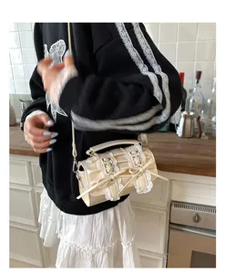 Detalle de bolso cilíndrico crema con encaje y lazos usado como bolso bandolera casual